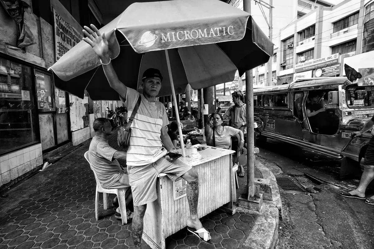 Black and white street photo capturing vibrant urban life in Manila with vendors.
