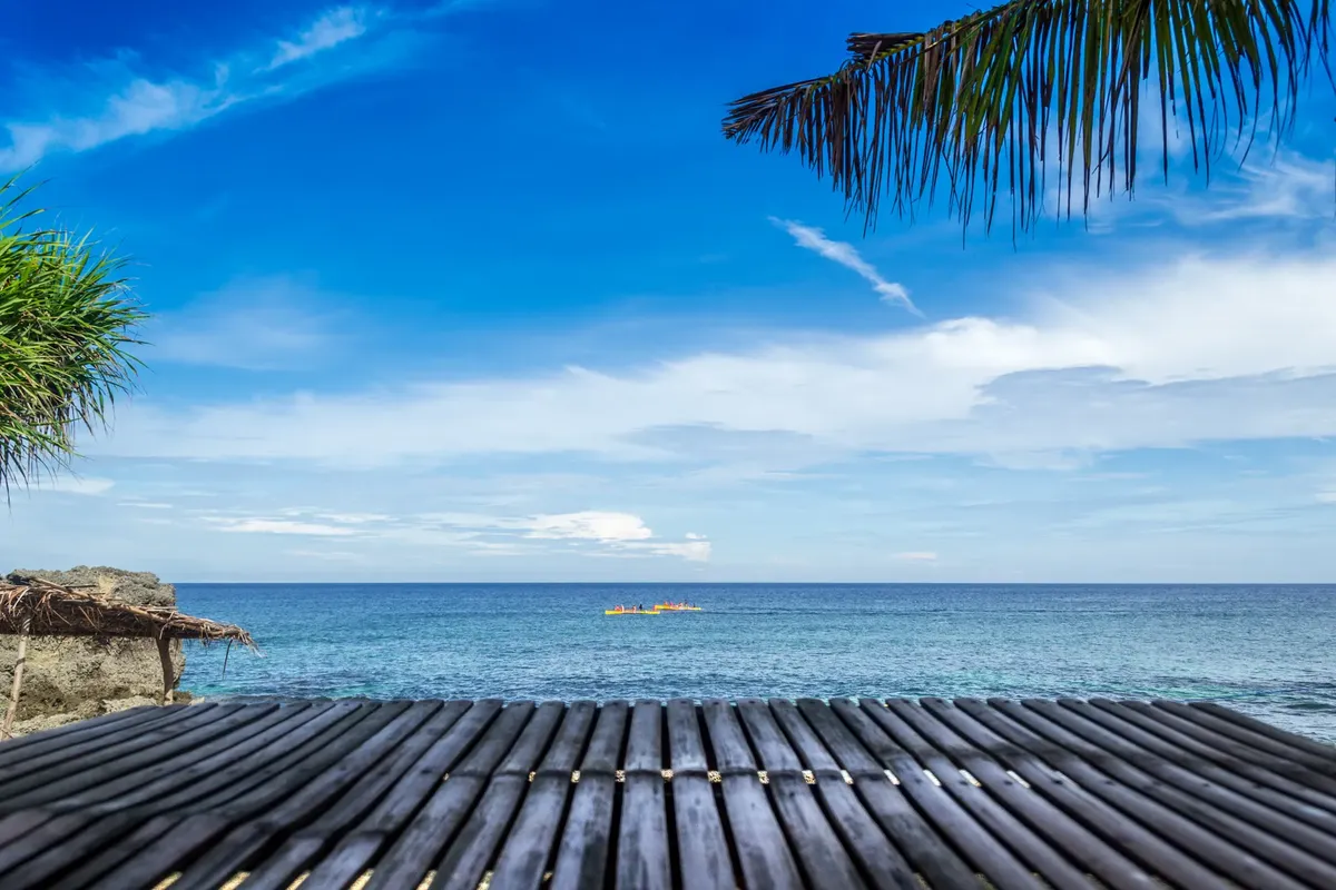 Serene tropical beach in Bolinao, Philippines with clear blue water and skies.
