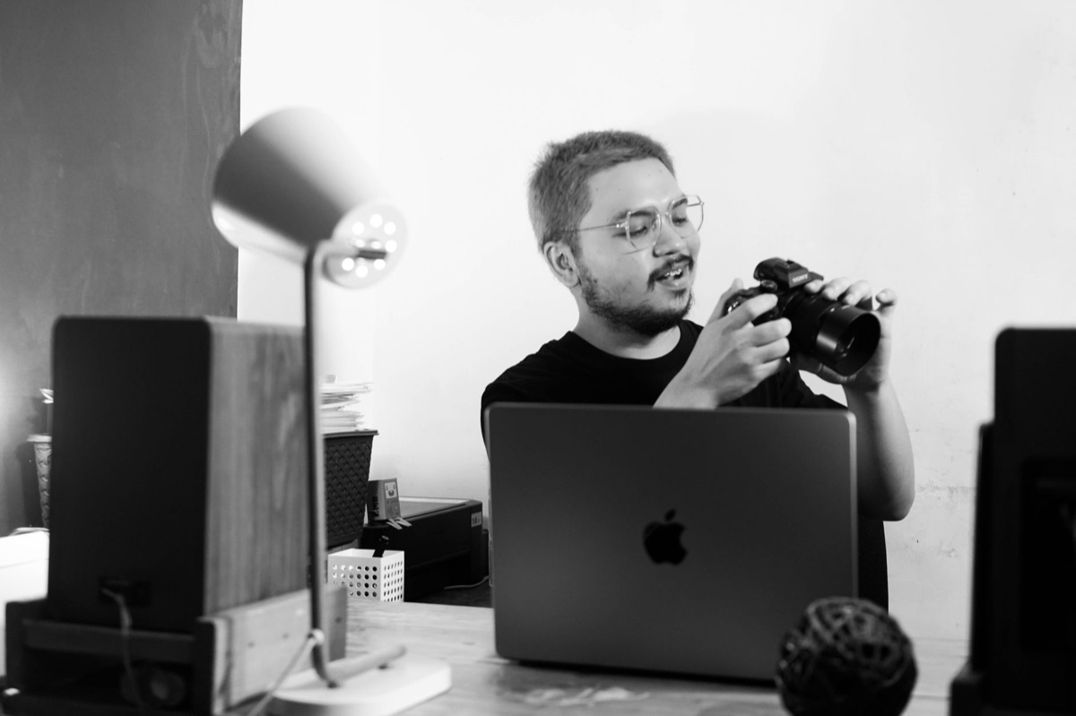 Filipino YouTuber with camera and laptop in global office